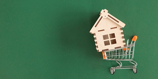 Shopping cart and home on green background property buying for\
invest concept