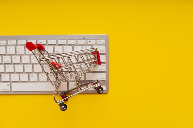 Shopping cart on a keyboard on a yellow background Online shopping concept