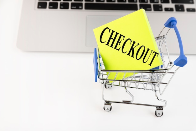 Photo shopping cart, laptop, text, checkout, on yellow paper. business