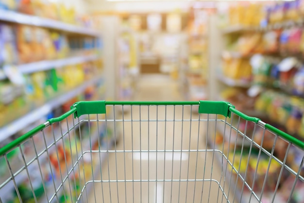 Shopping cart in Supermarket or convenience store Aisle and Shelves in blurry for background