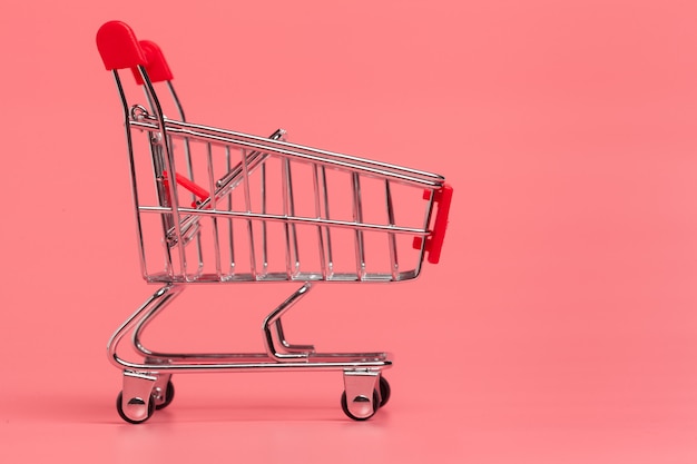 Shopping cart or supermarket trolley on pink background