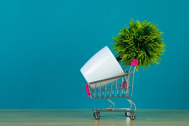 Shopping cart or supermarket trolley with little decoration tree on table