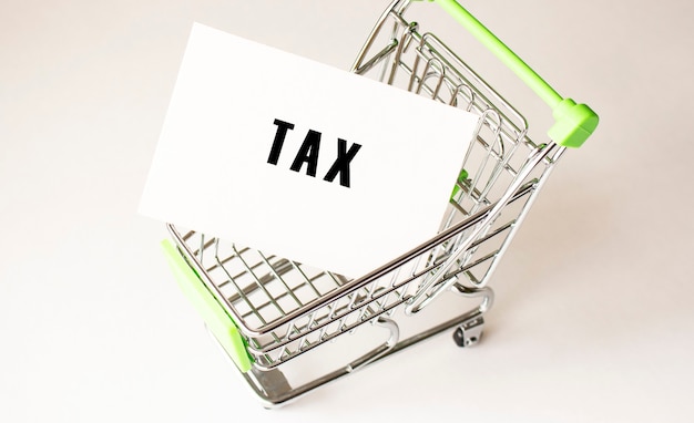 Shopping cart and text TAX on white paper