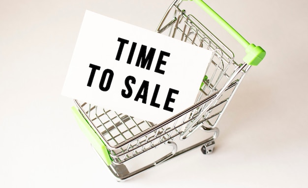 Photo shopping cart and text time to sell on white paper. shopping list concept on light background.