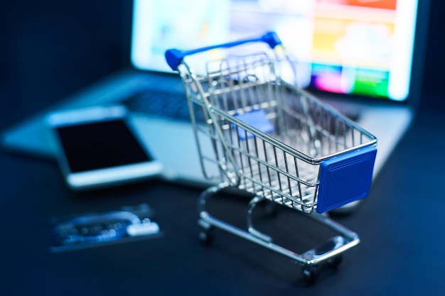 Photo shopping cart or trolley in front of laptop online marketing and business trading concept selected focusing
