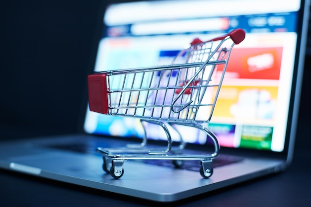 Photo shopping cart or trolley in front of laptop online marketing and business trading concept