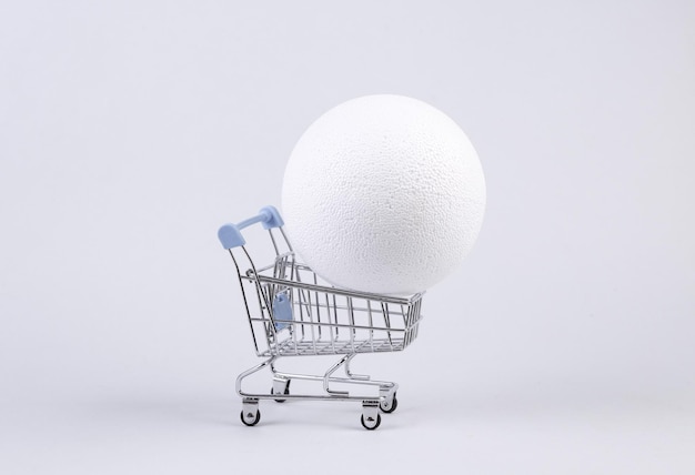 Shopping cart with ball on white background