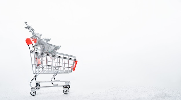 白い背景で隔離のクリスマスツリーとショッピングカート。クリスマスと新年の準備の概念。