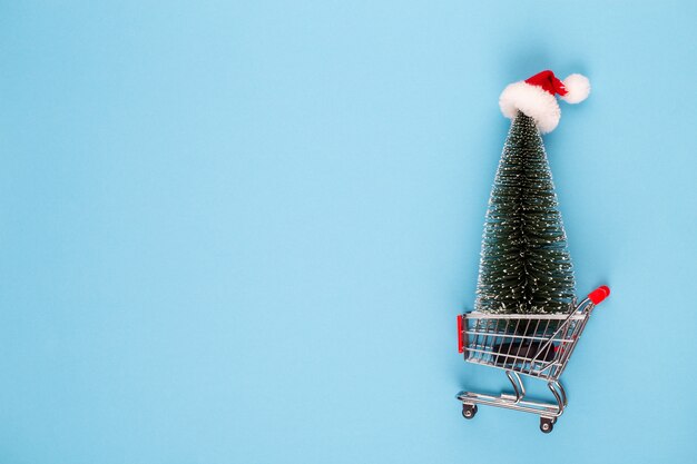 Foto carrello con l'albero di natale sulla tavola rossa.