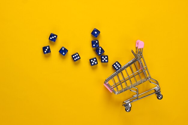 Shopping cart with dice on yellow background. Good luck shopping. Top view