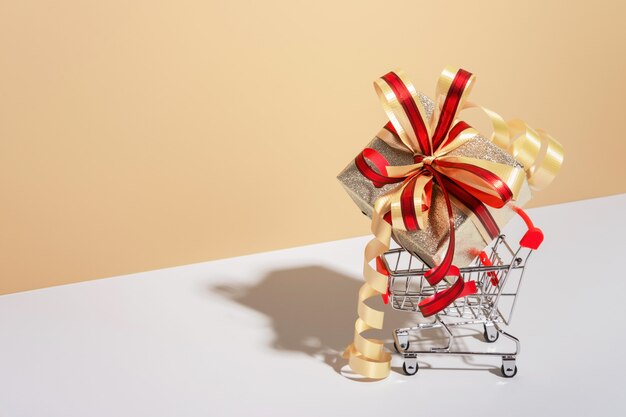 Shopping cart with gift box on beige