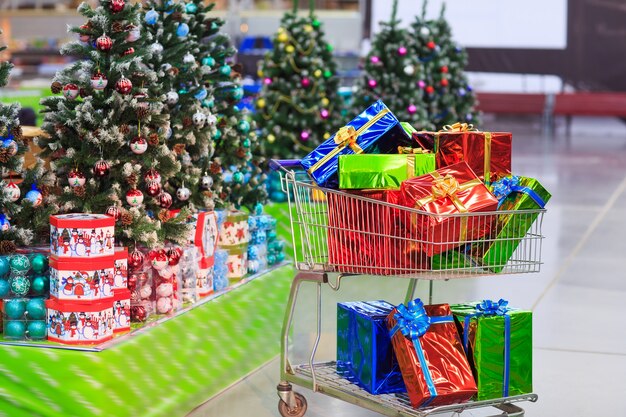 Shopping cart with gifts in supermarket background