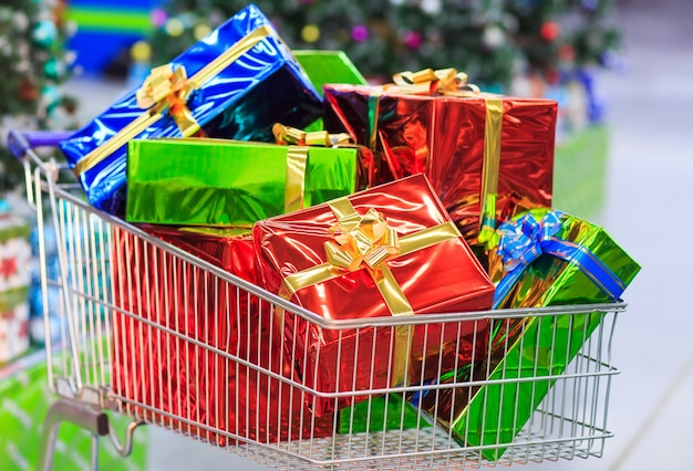 Shopping cart with gifts in supermarket background