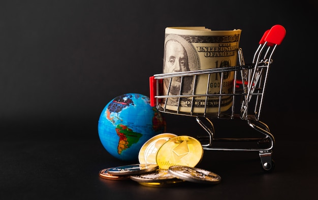 Photo shopping cart with golden coins, tiny globe and 100 dollars in the cart