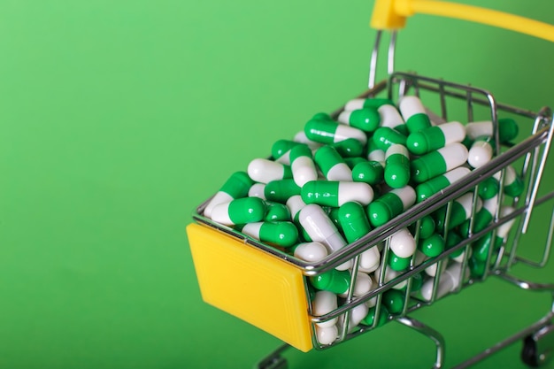 Shopping cart with medical pills on a green background