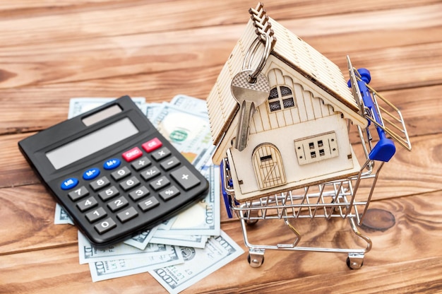 Shopping cart with model of house money and calculator on the table