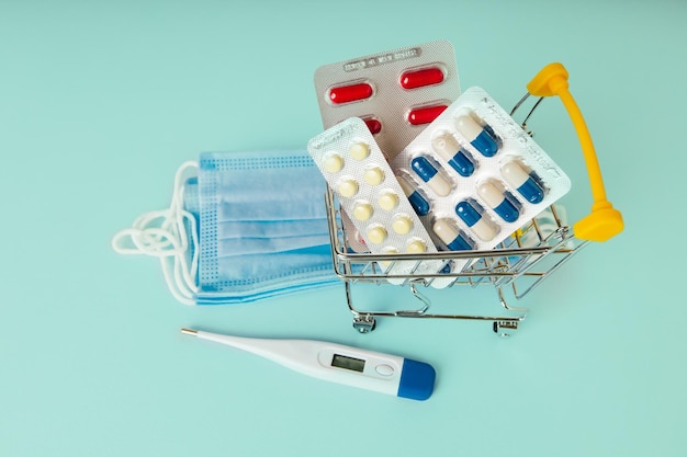 Shopping cart with pills and stack of masks The concept of medicine and the sale of drugs