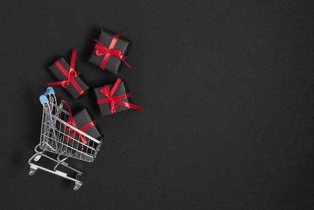 Shopping cart with presents top view on black background Black Friday template for design