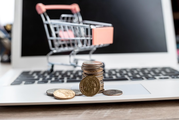 Shopping cart with stack of us coins on laptop Finance concept Online shopping