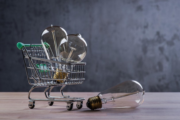 Shopping cart with vintage bulbs on wooden surface