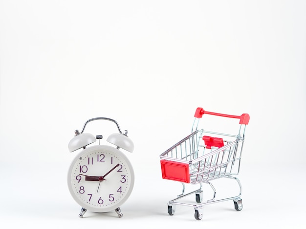 Shopping concept of cart and analog clock on the white background 