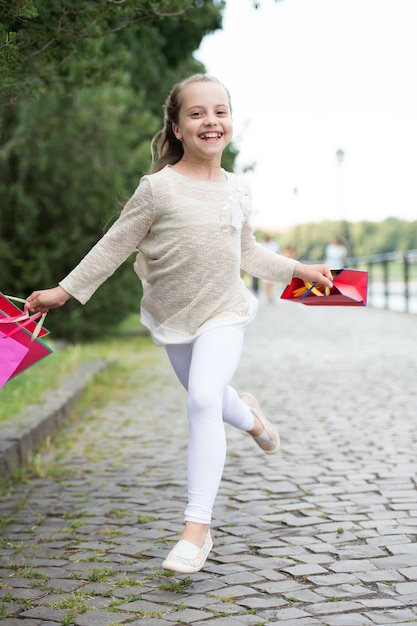 Concetto di acquisto. bambina carina che corre con le borse della spesa rosa