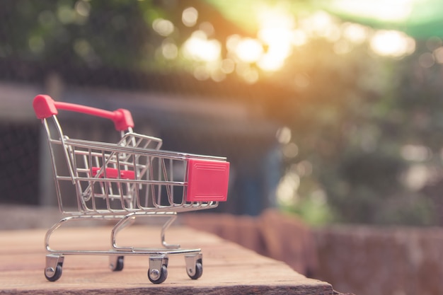 Shopping concept - Empty red shopping cart on brown wood table. online shopping consumers can shop from home and delivery service. with copyspace