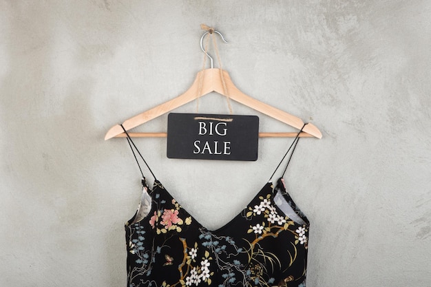 Photo shopping discount concept blackboard with text big sale and dress in floral pattern on a hanger