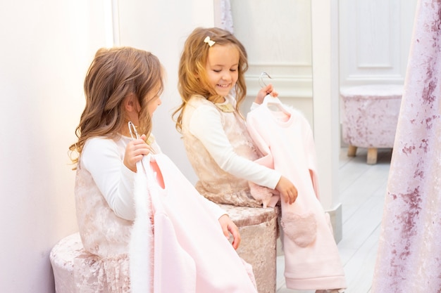 Shopping. discounts. little girl shopaholic. girl trying on a beautiful dress gently pink in the fitting room of the boutique. shopping center, shopping. emotions