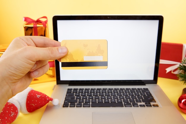 shopping online concept. Credit card and laptop with christmas gifts and boxes.