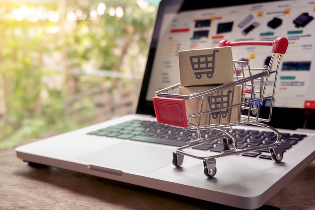 Shopping online concept - Parcel or Paper cartons with a shopping cart logo in a trolley on a laptop keyboard. Shopping service on The online web. offers home delivery.