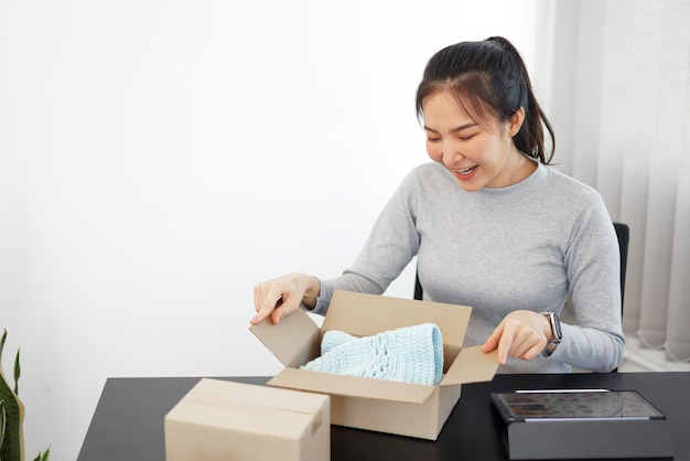 Shopping online concept a smiling woman unboxing an arriving parcel to check the products she bought after waiting with an effort.