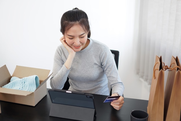 온라인 쇼핑 개념 온라인 쇼핑 응용 프로그램에서 온라인 구매를 용이하게 하기 위해 신용 카드를 사용하는 젊은 여성.