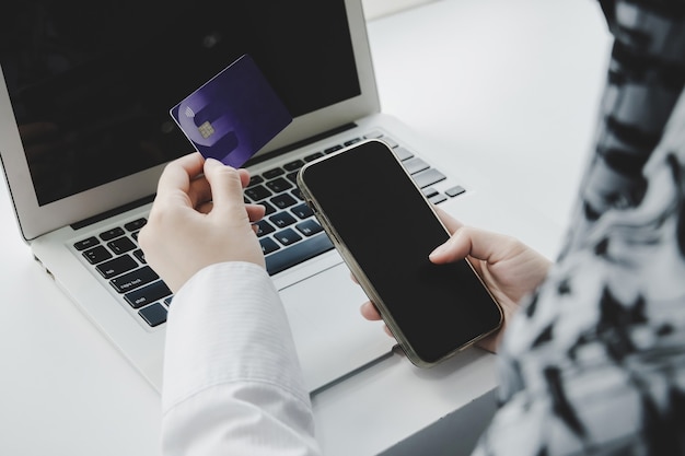 Shopping Online. hand holding credit card and online shopping on laptop computer on desk at home office, internet, digital marketing, mobile banking, online payment and digital technology concept