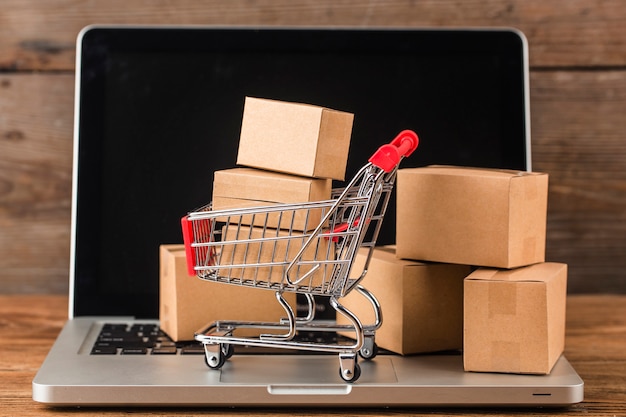 Photo shopping online at home concept. cartons in a shopping cart on a laptop keyboard.