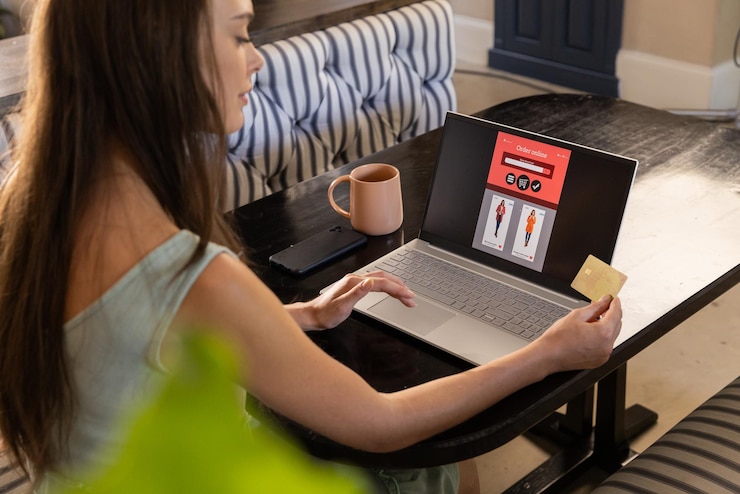 Photo shopping online woman using laptop and holding credit card at home