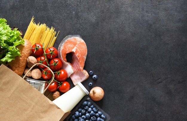 Foto la spesa in un sacchetto di carta: salmone, peperone, melanzane, noci, pane, uova. consegna del cibo. pubblicità. supermercato.