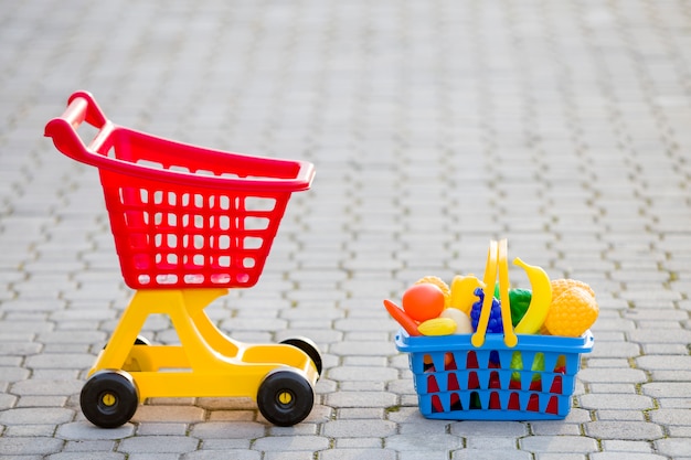 Shopping pushcart and a basket with toy fruits and vegetables.