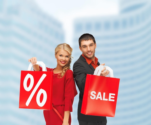 shopping and sale concept - man and woman with shopping bag outdoors