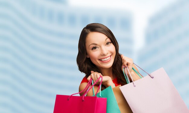 shopping, sale, gifts, christmas, x-mas concept - smiling woman in red dress with shopping bags