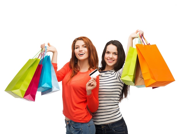 shopping, sale and gifts concept - two smiling teenage girls with shopping bags and credit card