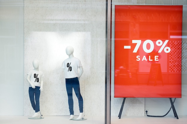 Photo shopping sale window display with mannequins wearing tshirts with sign of sale, dummies in the store, sale and fashion concept.