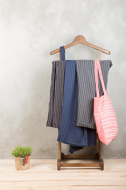 Shopping and style concept clothes rack with trendy striped pants and coral eco tote bag