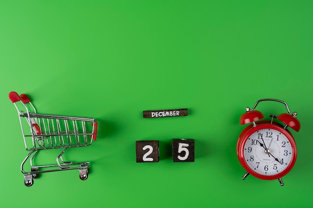 Shopping time concept. Supermarket trolley with alarm clock and date of celebrate 25 December