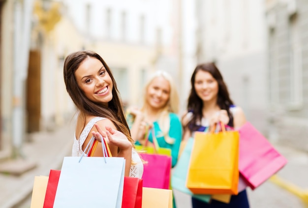 shopping and tourism concept - beautiful girls with shopping bags in ctiy