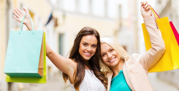 shopping and tourism concept - beautiful girls with shopping bags in ctiy