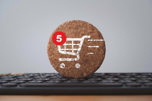 Shopping trolley cart and notification print screen to round wooden block on computer keyboard for online shopping and ecommerce business concept