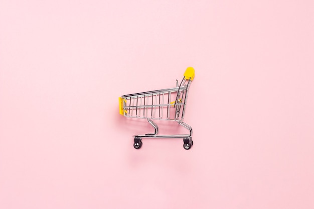 Shopping trolley from the supermarket on an isolated pink background. Shopping in the Mall, shop, shopping.