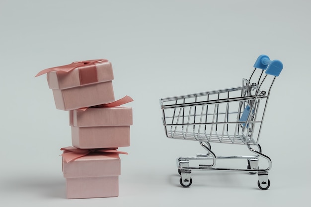 Shopping trolley and gift boxes with bows on white background. Composition for christmas, birthday or wedding.