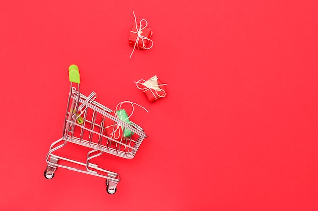 Shopping trolley on a red background with gifts, top view. Copy Space. Business, Sales Concept